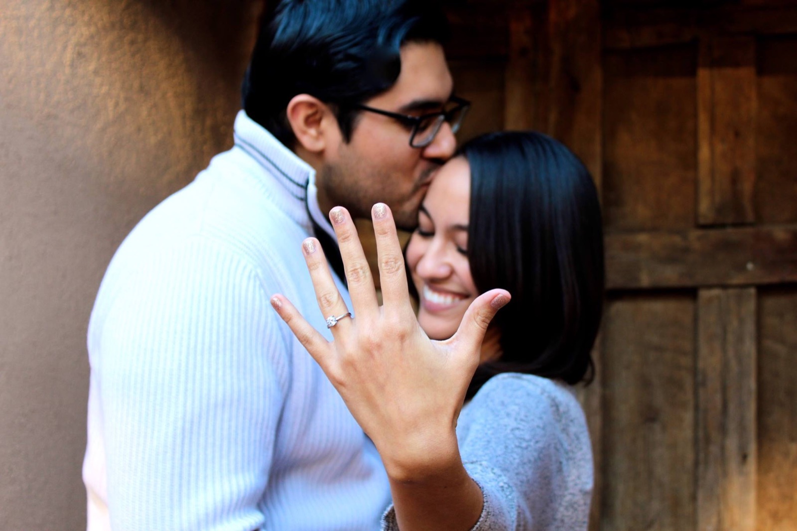 Just-engaged couple kissing while she shows the ring