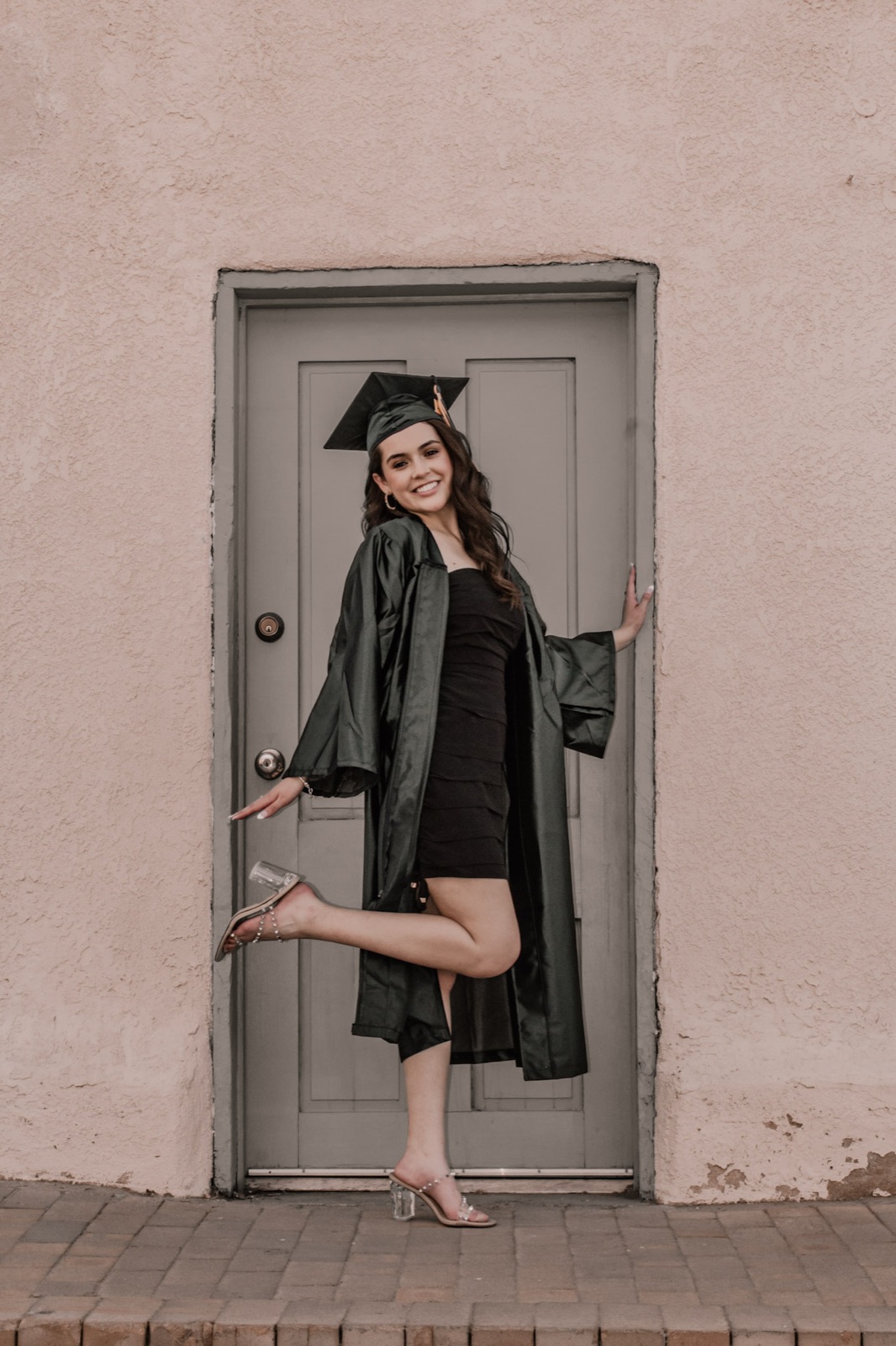 Graduate in cap and gown posing in an adobe doorway