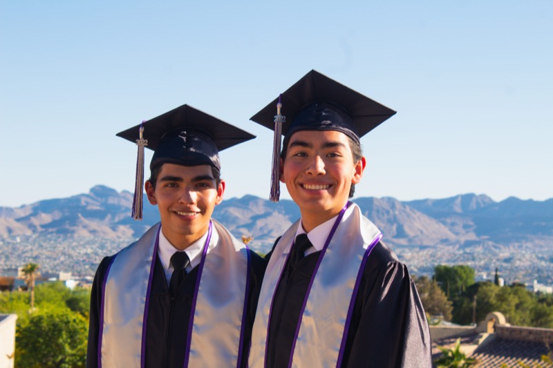 Two graduates with the El Paso mountains behind them