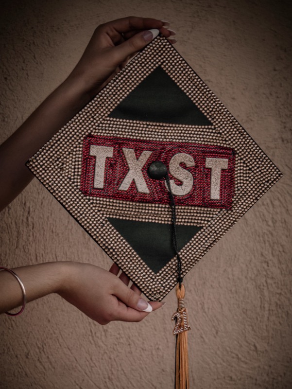 Graduate holding a TX-ST sign