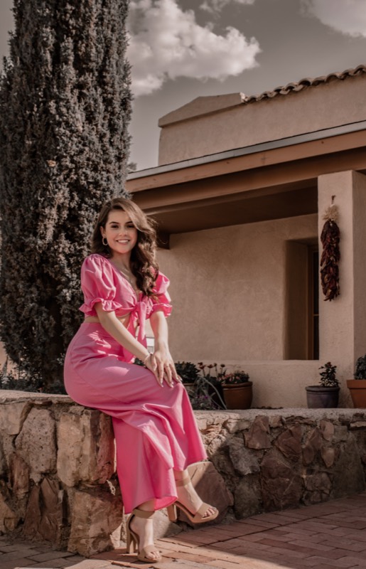 Quinceañera in pink beside an adobe wall