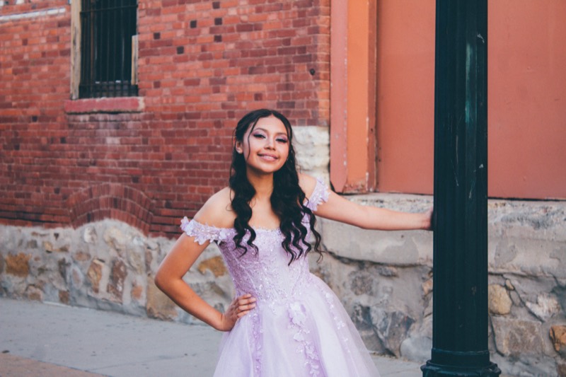 Quinceañera in pink against a brick wall